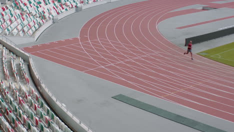 Hombre-Afroamericano-De-Raza-Negra-Practicando-Carrera-En-Una-Pista-De-Estadio-Vacía-Temprano-En-La-Mañana.-Fotografía-Tomada-Con-Lente-Anamórfica.